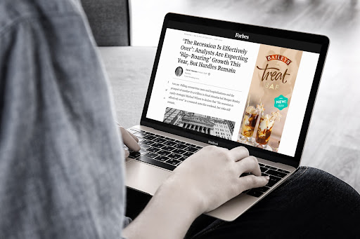 A Baileys Treat Bar online display ad shown beside a Forbes article on a laptop